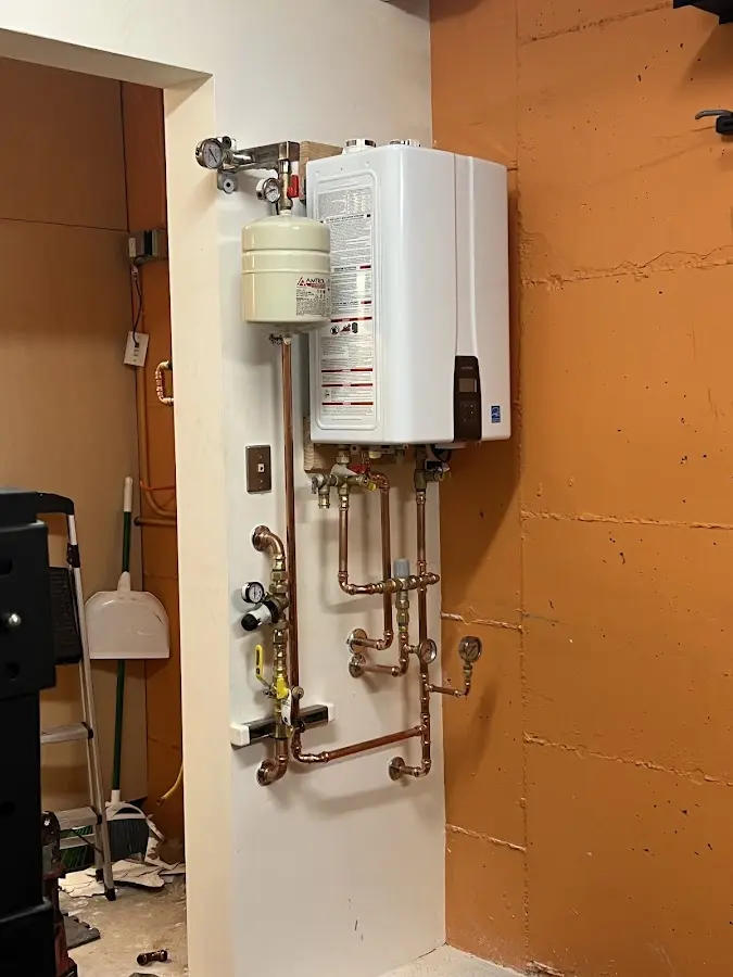 Plumbing technician inspecting water heater connections in Pimmit Hills